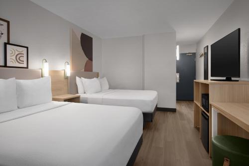 a hotel room with two beds and a flat screen tv at Spark by Hilton Denver East I 70 in Denver