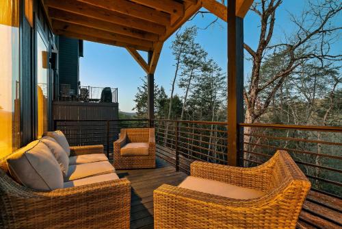 a deck with wicker chairs and chairs on a porch at Modern Luxury Pool Hot Tub & Near Water Parks in Sevierville