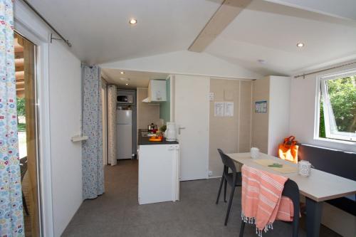 a kitchen and dining area of a caravan with a table and chairs at Domaine Le Petit Lac in Moustiers-Sainte-Marie