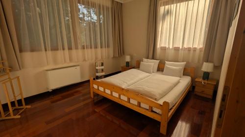 a bedroom with a large bed and two windows at Mooi Panzió in Nagyatád