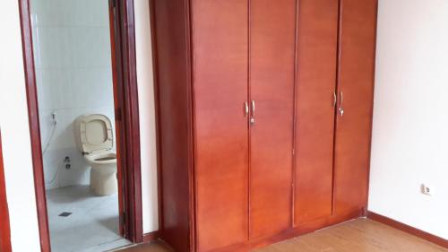 a bathroom with a toilet and some wooden cabinets at Sport Guest House in Addis Ababa