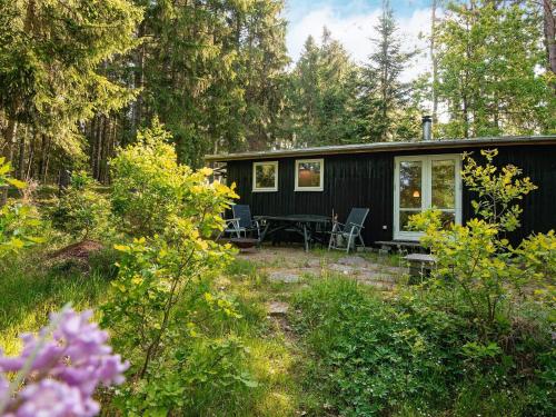 a black cabin in the woods with a table and chairs at 4 person holiday home in Bryrup-By Traum in Bryrup