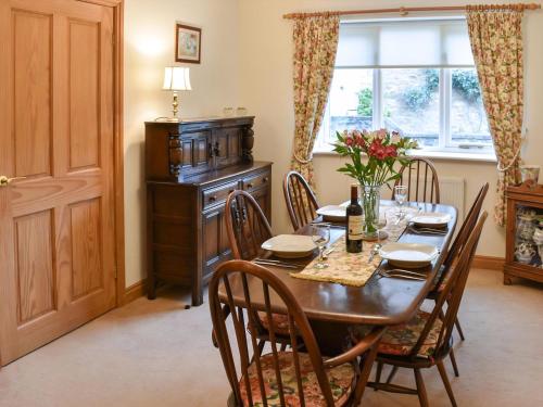 a dining room with a table and chairs and a window at Beckside Cottage in Bishop Monkton