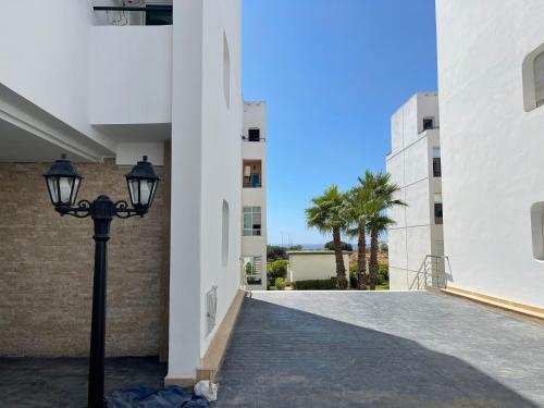 a street light next to a building with a palm tree at Casa étoile, Appartement avec piscines, vue sur mer et accès à la plage à Achakar Hill, Tanger in Tangier