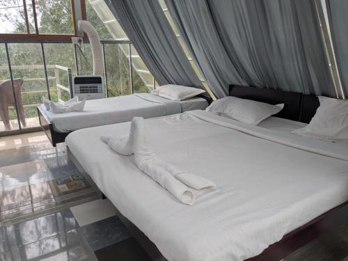 two beds with white sheets and pillows in a room at Ashokavanam Heritage Village by N Square in Kanthalloor