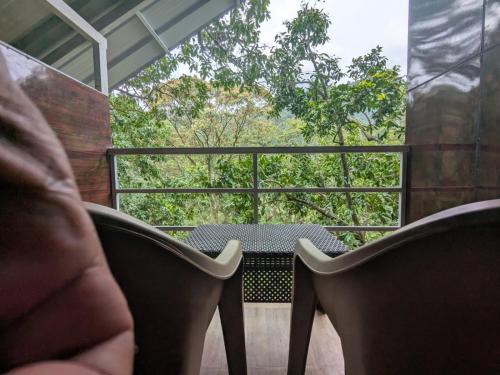 a person sitting on a balcony with a table and chairs at Ashokavanam Heritage Village by N Square in Kanthalloor