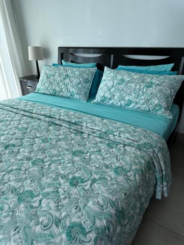 a bed with a blue comforter and pillows at Lulu Village - Beach - Pool - Pet Friendly in Coclé