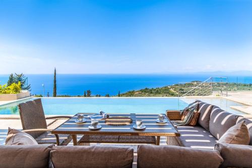 a patio with a table and chairs next to a pool at Villa Andromeda Sunset in Tsoukaladhes