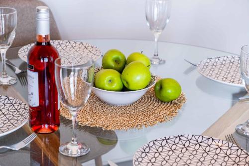 a glass table with a bowl of apples and a bottle of wine at Villa Andromeda Sunset in Tsoukaladhes