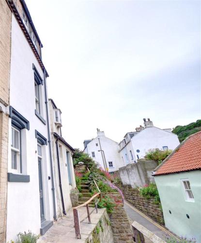 a narrow street with white houses and a bench at Hillsover in Staithes