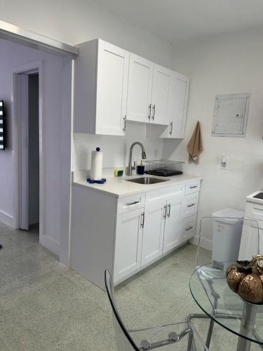 a kitchen with white cabinets and a sink and a table at Villa Clara ICON-Little Havana in Miami