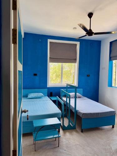 two beds in a blue room with a window at 234 Weligama in Pareiduwa