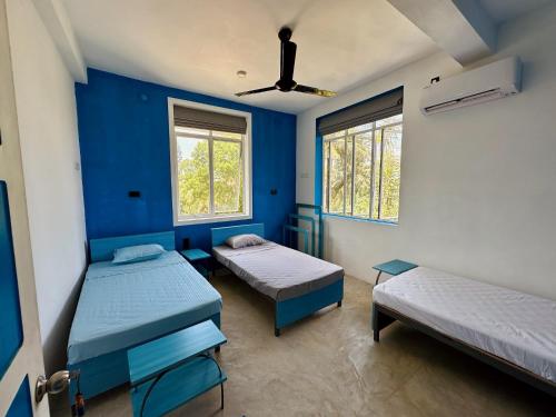 a blue room with two beds and two windows at 234 Weligama in Pareiduwa