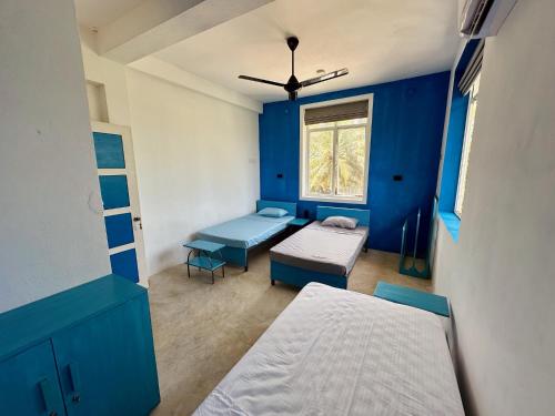 a blue room with two beds and a window at 234 Weligama in Pareiduwa