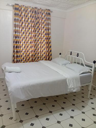 a white bed in a room with a window at Humility - Olive in Naro Moru