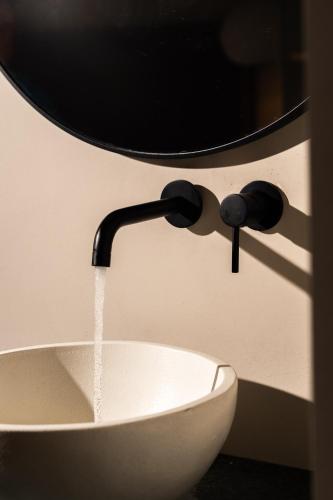 a water faucet pouring water into a white sink at Astoria Hotel in Agia Galini