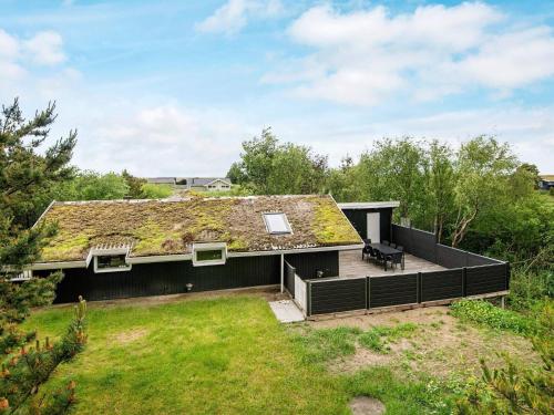a house with a grass roof with a deck at 6 person holiday home in Rømø in Bolilmark
