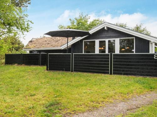 a house with a black fence and an umbrella at 6 person holiday home in Rømø in Bolilmark
