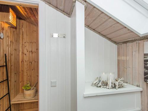 a room with white walls and a white shelf with a candle at 6 person holiday home in Rømø in Bolilmark