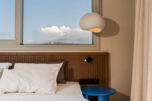 a bedroom with a window and a bed with a blue table at Astoria Hotel in Agia Galini