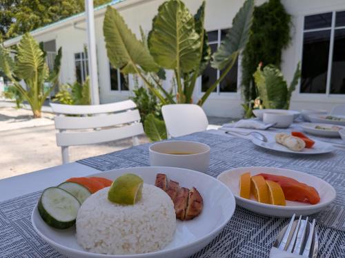 a table with plates of rice and fruit on it at Avi Guesthouse in Thoddoo