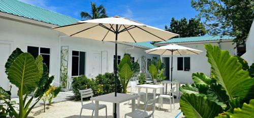 a group of tables and umbrellas in front of a building at Avi Guesthouse in Thoddoo