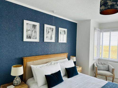 a bedroom with a bed and a blue wall at Large villa opposite beach in Great Yarnouth in Great Yarmouth