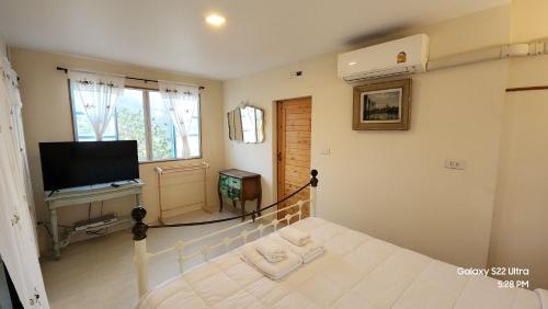 a bedroom with a bed and a flat screen tv at Flora Prairie at Mae Rim, Chiang Mai in Ban Tai