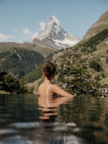 a woman in the water with a mountain in the background at Relais & Chateaux Schönegg in Zermatt