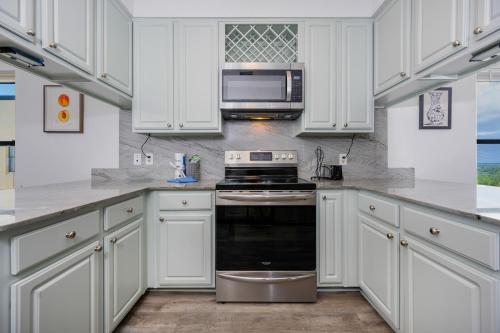 a white kitchen with a stove and a microwave at Phoenix II 2151 condo in Romar Beach