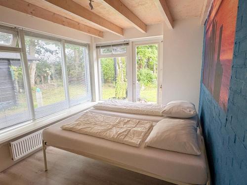 two beds in a room with two windows at Duinland 142 in Sint Maartensvlotbrug