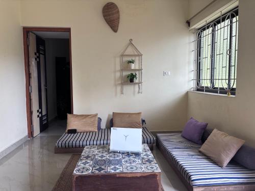 a living room with a couch and a laptop on a table at South Goa homestay near Rajbag Beach in Canacona