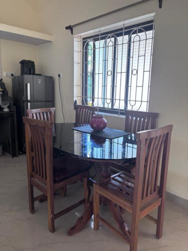 a dining room with a glass table and two chairs at South Goa homestay near Rajbag Beach in Canacona