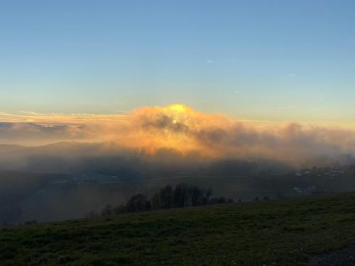 a view of a foggy field with the sun poking through the clouds at Kircher Hütte in Diex