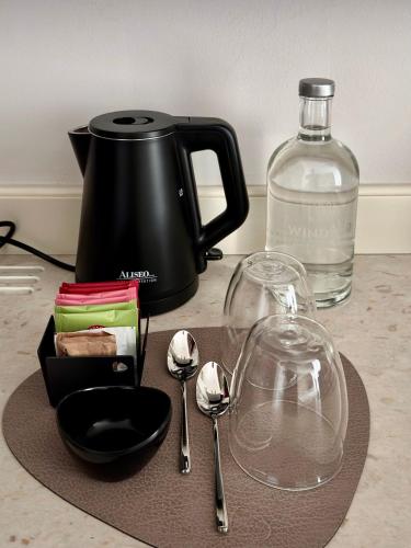 a counter with a coffee maker and spoons and a bottle at Windsor Merano Hotel & Suites in Merano