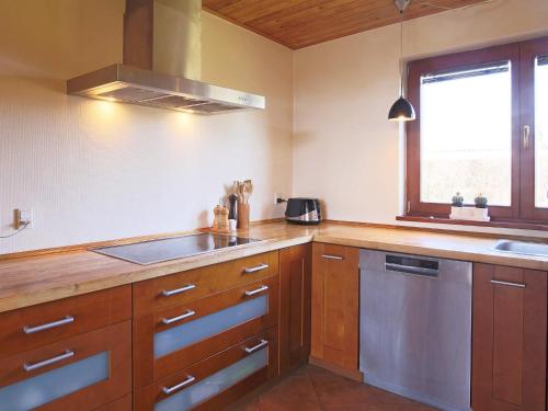 a kitchen with wooden cabinets and a sink and a window at 6 person holiday home in Kirke Hyllinge in Kirke-Hyllinge