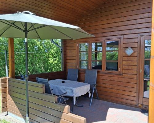a patio with a table and chairs and an umbrella at Ferienhof Schlottmann in Achtrup