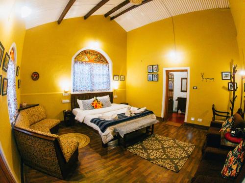 a yellow room with a bed and a chair in it at LA Address Retreat - The Heritage Homestay in Ooty