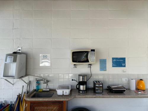 a kitchen counter with a microwave and a sink at Ao Mar - Hospedagem in São Sebastião