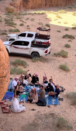 a group of people sitting on blankets in front of a truck at Shakria Bedouin Life Camp in Wadi Rum