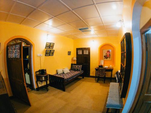 a living room with a couch and yellow walls at LA Address Retreat - The Heritage Homestay in Ooty