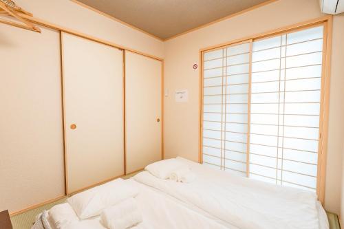 a bedroom with a white bed and a large window at ｄｐ小山町 in Machida