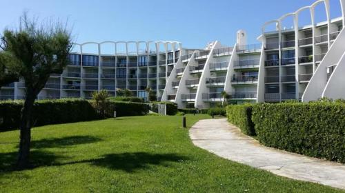 a large building with a grassy yard in front of a building at 1ere ligne, Vue mer, piscine privée, Wifi, Clim in La Grande-Motte