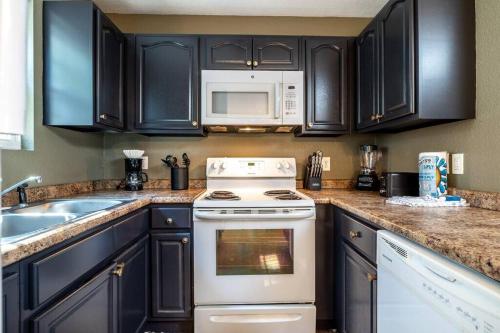 a kitchen with black cabinets and a white stove top oven at Peaceful Getaway Hot Tub Perfect Location in Sevierville