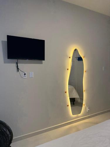 a bedroom with a tv and a mirror on the wall at Mirante do Ipiranga Apartment in Guarapari