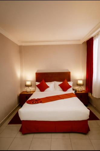 a bedroom with a large bed with red pillows at Queen Hotel in Addis Ababa