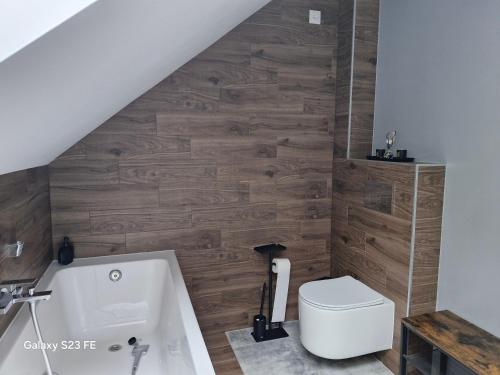 a bathroom with a toilet and a wooden wall at Kaszuby Punkt Klonowo Przywidz sauna klima basen in Przywidz