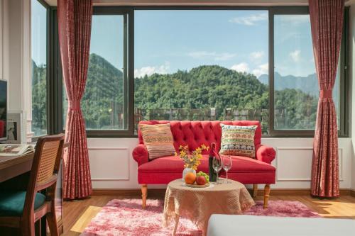 a living room with a red couch and large windows at Glow Sapa Hotel in Sa Pa
