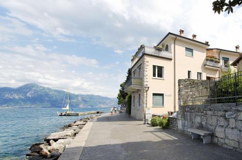 a building next to a body of water with a boat at Appartamento a 5 metri dal lago in Torri del Benaco