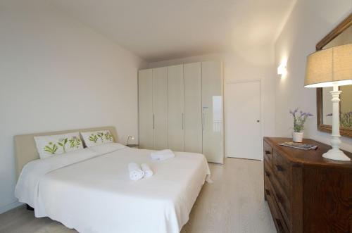 a white bedroom with a white bed and a dresser at Appartamento a 5 metri dal lago in Torri del Benaco